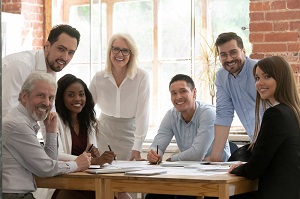 group of employees sitting around table smiling at camera